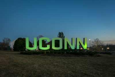 UConn sign in a field lit up in a sustainable green. 